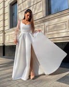 Rochie de mireasa albă din satin lungă, elegantă, cu șliț și mâneci transparente.
