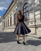 Rochie de ocazie neagră midi evazată cu mâneci lungi transparente și decolteu în V.