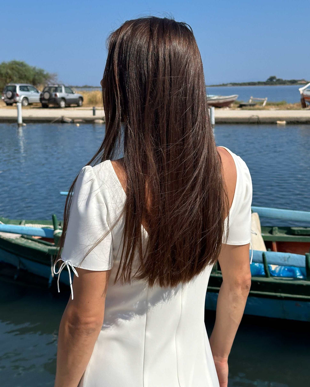 Rochie albă scurtă cloș cu mâneci, elegantă și feminină, lângă apă.