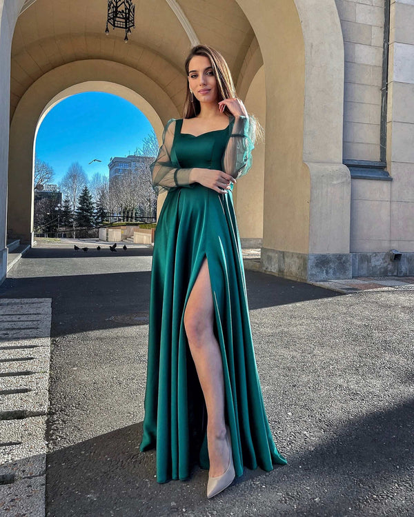 Rochie lunga verde smarald din satin cu mâneci din tulle și șlit lateral, eleganță sofisticată.