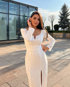 Rochie albă elegantă cu slit, mâneci lungi și fermoar la spate, ideală pentru evenimente speciale.