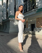 Rochie alba elegantă cu bretele și slit, confecționată din crep elastic, perfectă pentru ocazii speciale.