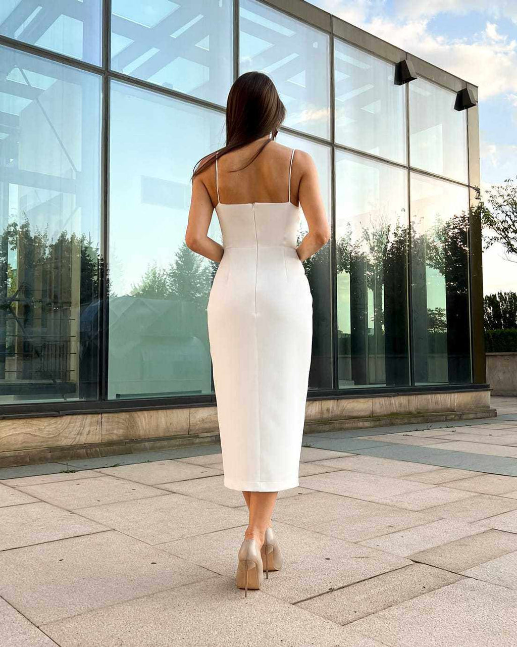 Rochie eleganta alba cu căptușeală, tăietură centrală și detalii decorative, vedere din spate.