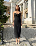 Rochie eleganta de ocazie neagră din crep elastic cu pliuri și slit central, ideală pentru evenimente formale.